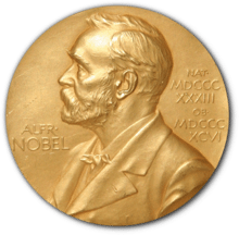 A golden medallion with an embossed image of Alfred Nobel facing left in profile. To the left of the man is the text
